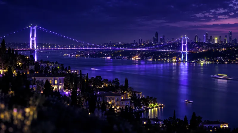 Mavi saatte ışıklarla aydınlanan Boğaz köprüsü ve İstanbul silueti